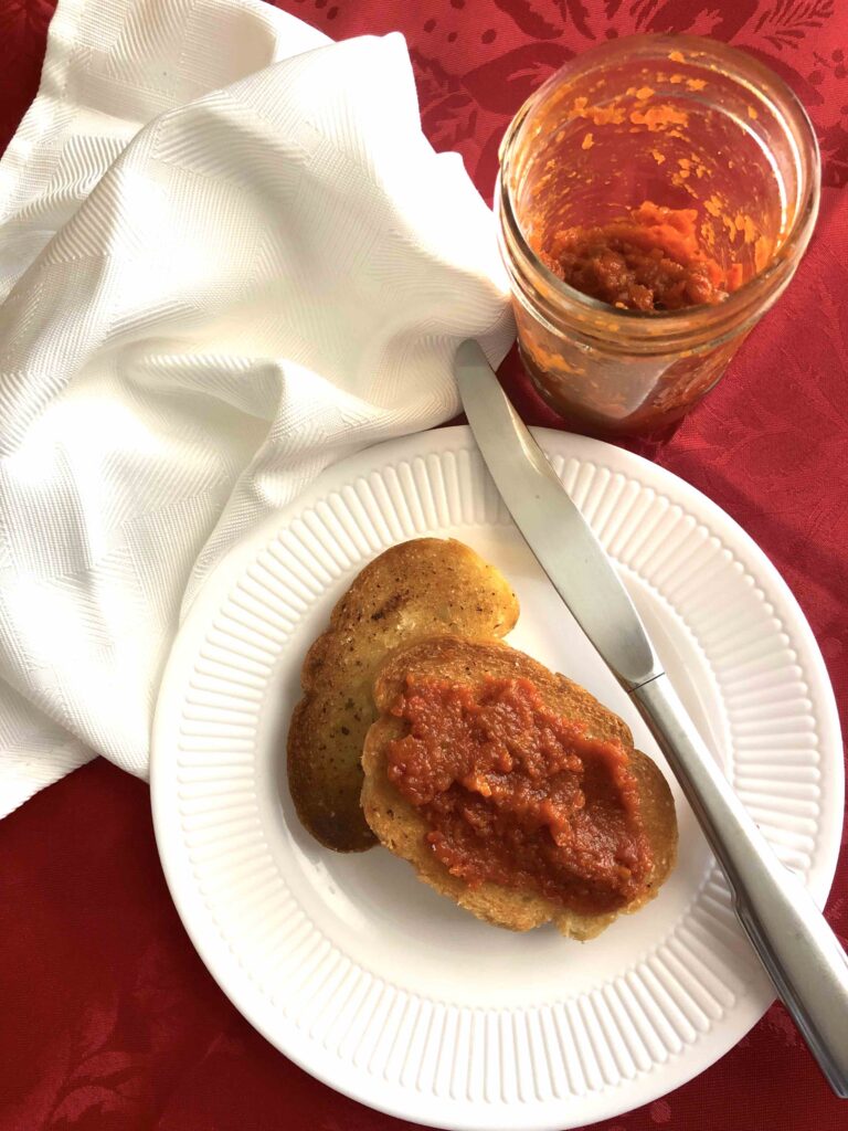 A bowl of homemade Bulgarian Lyutenitsa, a vibrant red spread made from roasted peppers, tomatoes, eggplant, and herbs